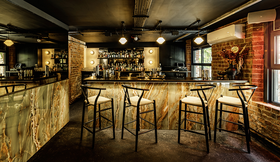 A lit bar setting tiled with onyx emerald polished porcelain wall tiles